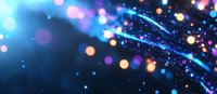 Glowing blue and purple bokeh lights with shimmering particles creating magical atmosphere against dark background. Abstract festive backdrop with blurred motion effect.