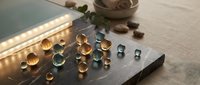 Gemstones and crystals in various cuts and colors arranged on dark surface with natural lighting, showcasing amber, clear, and blue tones for jewelry design, gemology, and luxury product applications.