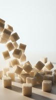 Falling brown and white sugar cubes cascading onto a pile against neutral background, isolated for design use in food, beverage, and culinary projects.