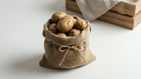 Fresh organic potatoes in rustic burlap sack with rope tie on white background. Natural farm produce for cooking and healthy eating concepts.