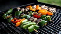 Colorful vegetable and mushroom skewers grilling on barbecue grate with bell peppers, zucchini and button mushrooms. Fresh summer outdoor cooking.