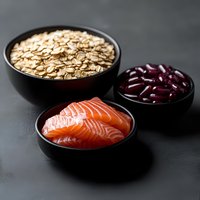 Fresh salmon slices, rolled oats and red kidney beans in black ceramic bowls on dark background, healthy protein and fiber rich ingredients for cooking.