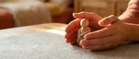 Protective hands cupping wooden figure symbolizing care, safety, insurance and human protection in warm home environment for business concepts.