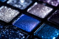 Shimmering eyeshadow palette with metallic blue and silver makeup colors in compact squares for beauty and cosmetics applications.
