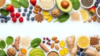 Healthy superfood ingredients arranged on white background with fresh fruits vegetables nuts seeds and grains for nutritious diet and wellness lifestyle.