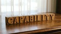 Wooden letter blocks spelling CAPABILITY on rustic table surface near bright window for business motivation and personal development concepts.