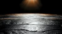 Dramatic stone or concrete surface with bright sunburst light effect against dark background creates atmospheric mood for product display or presentation background.