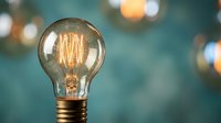 Vintage Edison light bulb with glowing filament against blurred background. Retro incandescent lamp with warm amber light for creative projects and designs.