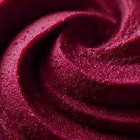 Smooth swirled texture of burgundy sorbet or ice cream in macro shot showing creamy frozen dessert surface with rich deep red color and velvety consistency.