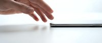 Hand reaching toward a sleek black stylus pen on white surface, representing digital design, technology interaction, and modern creative tools for professionals.
