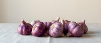 Fresh red onions with papery skin arranged in a row on neutral surface for cooking and culinary use.