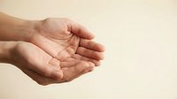 Open cupped hands in protective gesture against neutral beige background, symbolizing care, support, giving and receiving help in minimalist composition.