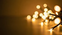 Warm golden string lights creating soft bokeh effect on dark background for festive decoration and cozy atmosphere during holidays and celebrations.