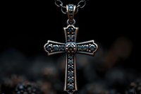 Ornate silver cross pendant with blue gemstones on dark background, featuring intricate metalwork details and vintage-style religious jewelry design.