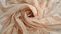 Delicate nude pink silk fabric with sparkly glitter texture swirled in elegant folds creating romantic dreamy background pattern for wedding and fashion designs.