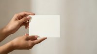Female hands holding blank white card mockup against neutral beige background for branding presentation and marketing materials design template.