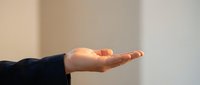 Open palm of a person wearing dark sleeve against neutral background, isolated hand gesture for design, presentations, and commercial use.