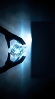 Hands protecting glowing crystal sphere with bright light rays in dark atmospheric setting for spiritual and energy healing concepts.