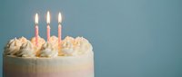 Birthday cake with lit candles and cream frosting on blue background for celebration party dessert concept.