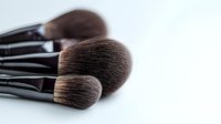 Professional makeup brushes with soft brown bristles and black handles against white background, close-up view showing texture and detail for cosmetic and beauty industry use.