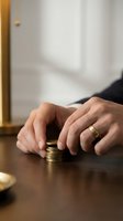 Person with wedding band stacking coins on wooden table, symbolizing financial planning, savings, and wealth management for business and personal finance concepts.