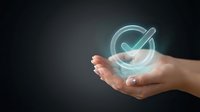 Hand holding glowing holographic checkmark symbol on dark background representing approval, success, verification and quality assurance concepts.
