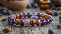 Handcrafted gemstone bracelet with amethyst and agate beads on rustic wooden background with blueberries and almonds, showcasing natural healing stones and jewelry.