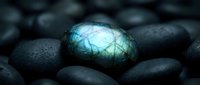 Glowing labradorite gemstone with blue-green iridescent flash surrounded by dark smooth river stones creating mystical mineral display for jewelry and healing concepts.