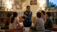 Adult male, Caucasian, teacher or educator, wearing casual blue cardigan, reading to diverse group of young children seated on floor in cozy, well-lit classroom or home learning space with bookshelves and warm lighting.