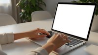 Professional woman typing on laptop with blank white screen in modern office workspace with plants and natural lighting for business presentations.