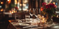 Elegant restaurant table setting with wine glasses, candles, and red rose bouquet in warm ambient lighting, creating romantic dining atmosphere.