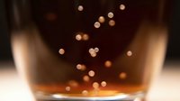 Whiskey or bourbon splashing in glass with bokeh light effects, ideal for beverage, alcohol, and bar-related design projects.