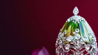 Ornate jeweled Easter egg with colorful enamel panels and crystal decorations on burgundy background for luxury holiday celebrations and gifts.