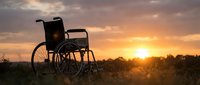 Empty wheelchair silhouetted against golden sunset in open field, symbolizing hope, recovery, and resilience for healthcare and wellness campaigns.