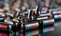 Metallic capsules with iridescent rainbow reflections scattered on dark reflective surface, macro photography with selective focus and bokeh effect.
