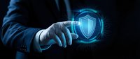 Businessman hand touching digital security shield icon with glowing blue holographic interface on dark background for cybersecurity and data protection concepts.
