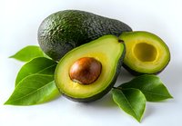Fresh ripe avocado cut in half showing creamy flesh and brown pit surrounded by green leaves on white background isolated for healthy cooking designs.