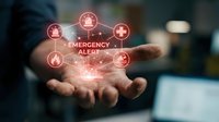 Businessman holding glowing emergency alert hologram with medical icons and warning symbols, representing crisis management, healthcare response, and digital emergency notification system.