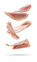 Flying sliced ham pieces isolated on white background. Levitating fresh pork meat cuts showing texture and marbling. Ready for design and commercial use.