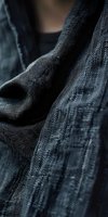 Charcoal gray herringbone weave fabric with soft folds and draping texture, showcasing natural fiber material for fashion, textile, and apparel design projects.