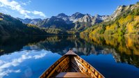 Wooden boat bow on calm mountain lake with autumn foliage reflection, peaceful wilderness adventure and outdoor recreation concept.