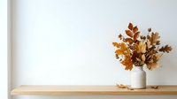 Dried autumn leaves in white ceramic vase on wooden shelf against white wall, fall home decor and interior styling for residential design projects.