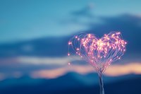 Glowing pink heart-shaped light trails against blurred mountain sunset backdrop creates magical romantic atmosphere for Valentine's Day designs and love concepts.
