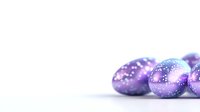 Shimmering purple Easter eggs with sparkly glitter decoration on white background, festive holiday composition with soft focus and copy space.