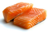 Fresh raw salmon fillets with distinctive orange color and marbled texture on white background, showcasing the natural fatty layers and clean cut preparation for cooking.