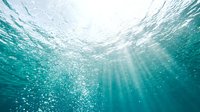 Underwater view with sunlight rays penetrating turquoise water and bubbles rising toward surface, suitable for ocean, marine, and nature backgrounds.