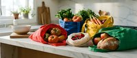 Fresh organic vegetables and fruits in colorful reusable shopping bags on modern kitchen counter promoting sustainable zero waste lifestyle.