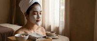 Young Asian woman enjoying spa facial treatment with clay mask in luxury wellness center relaxation therapy.