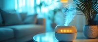 Essential oil diffuser emitting aromatic steam in modern living room with blue ambient lighting and decorative palm plant, creating relaxing atmosphere.