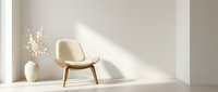 Modern beige accent chair with wooden legs in minimalist interior with dried flowers and natural sunlight creating warm shadows on neutral walls.
